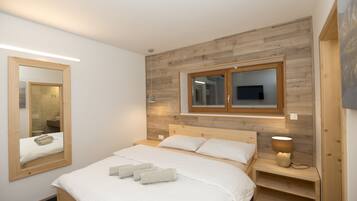 Quarto com cabeceira de madeira, um espelho grande, luminária de cabeceira e camas bem arrumadas.
