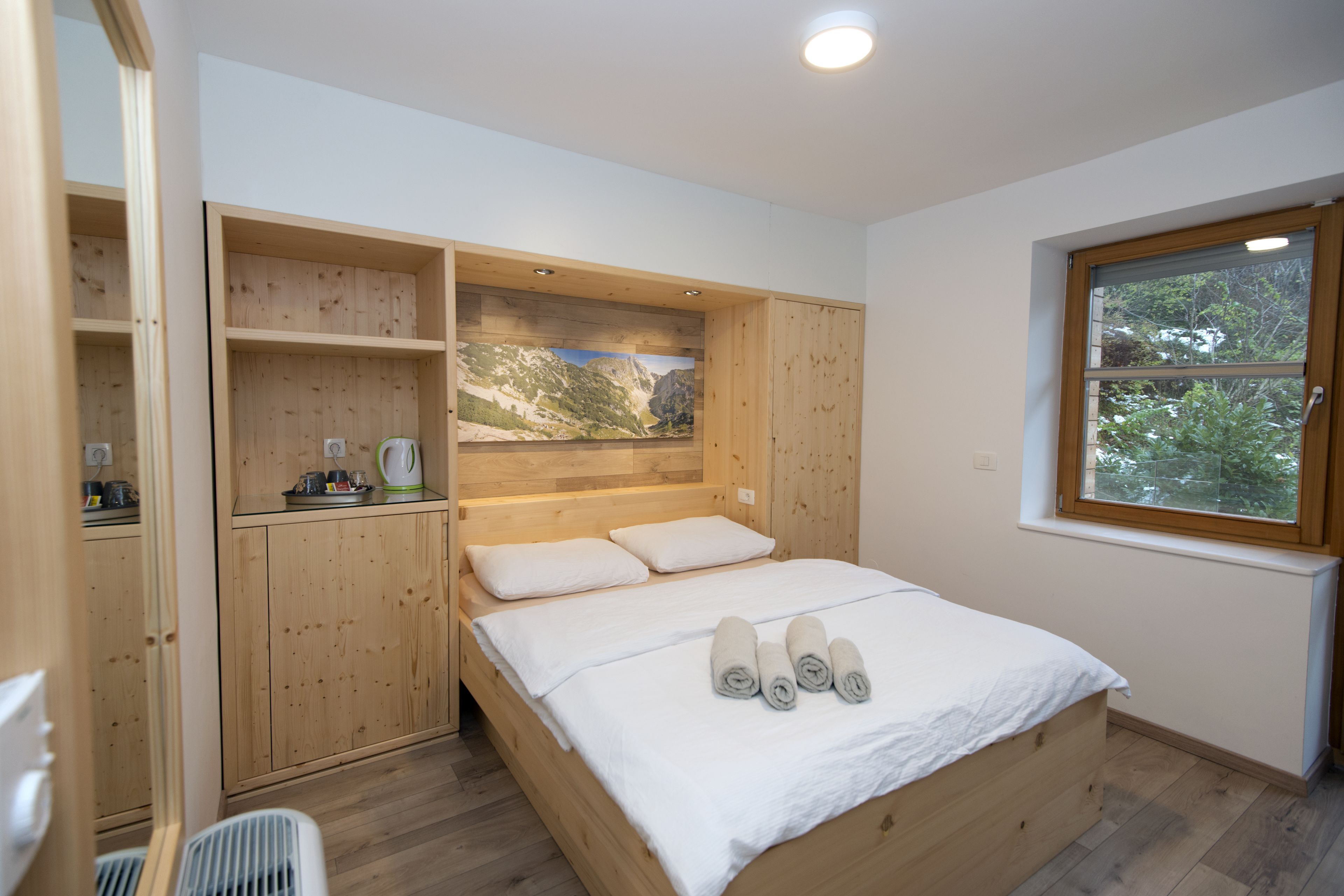 A bedroom with a wooden bed, built-in shelves, and a large window.