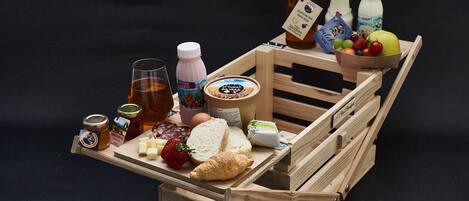 A wooden crate filled with various food items including bread, cheese, and fruits.