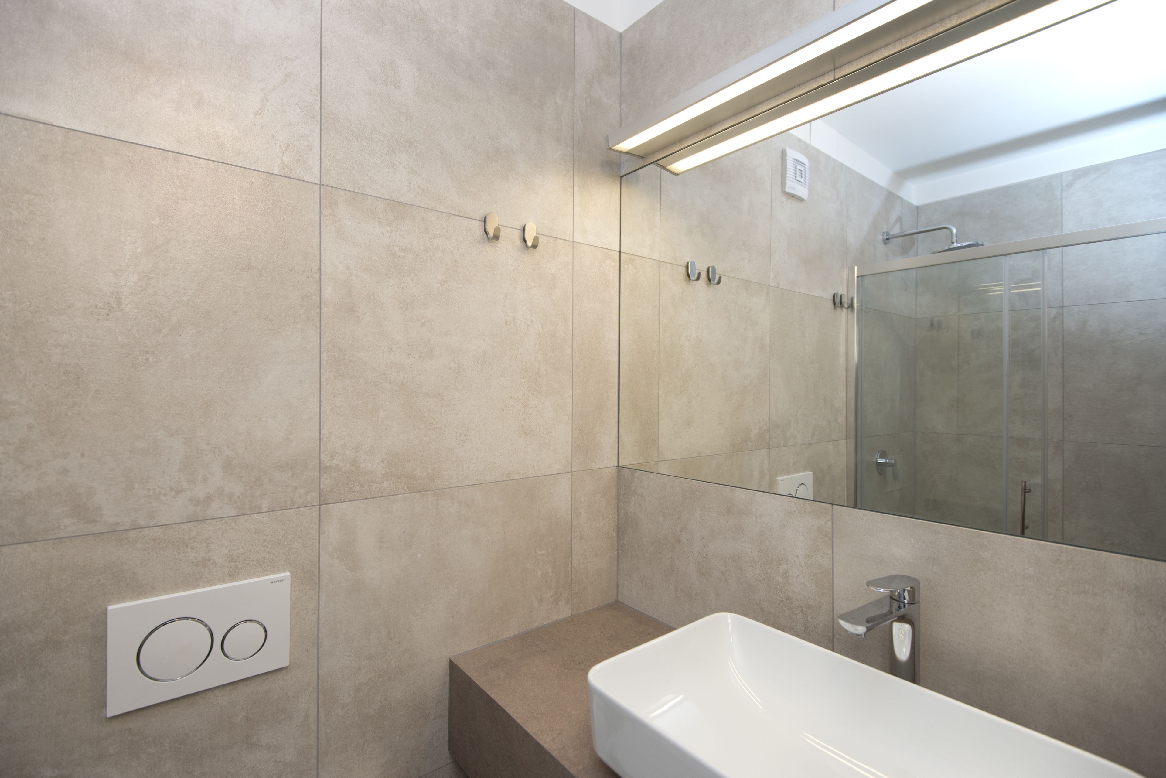 Un baño moderno con un espejo grande, una bañera y un perchero para toallas.