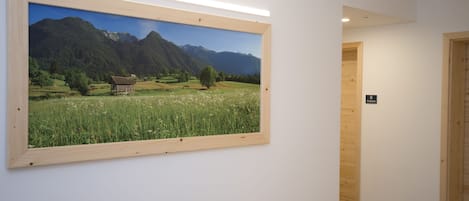 Un cuadro de paisaje enmarco colgado en una pared de un pasillo.