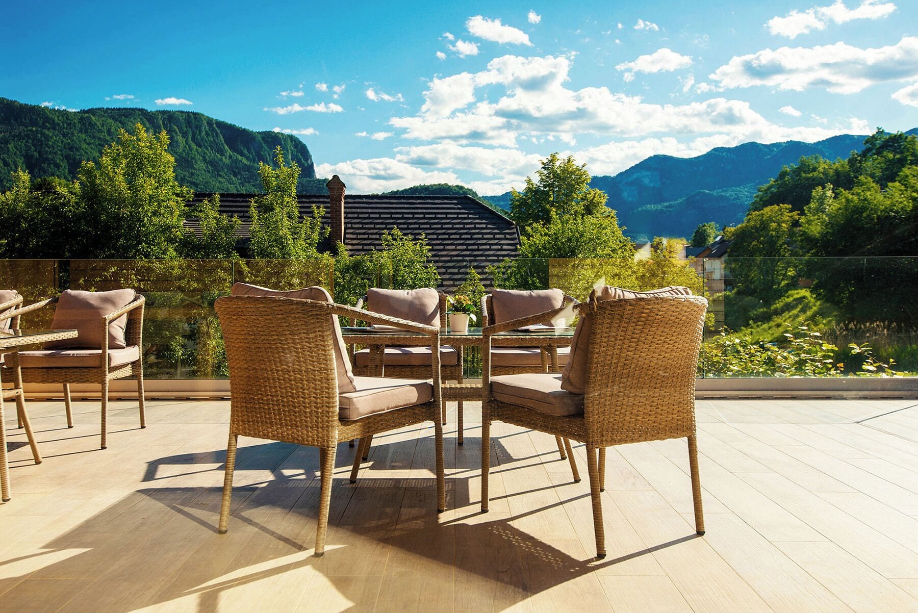 Een terras buiten met rieten meubels en uitzicht op bergen.