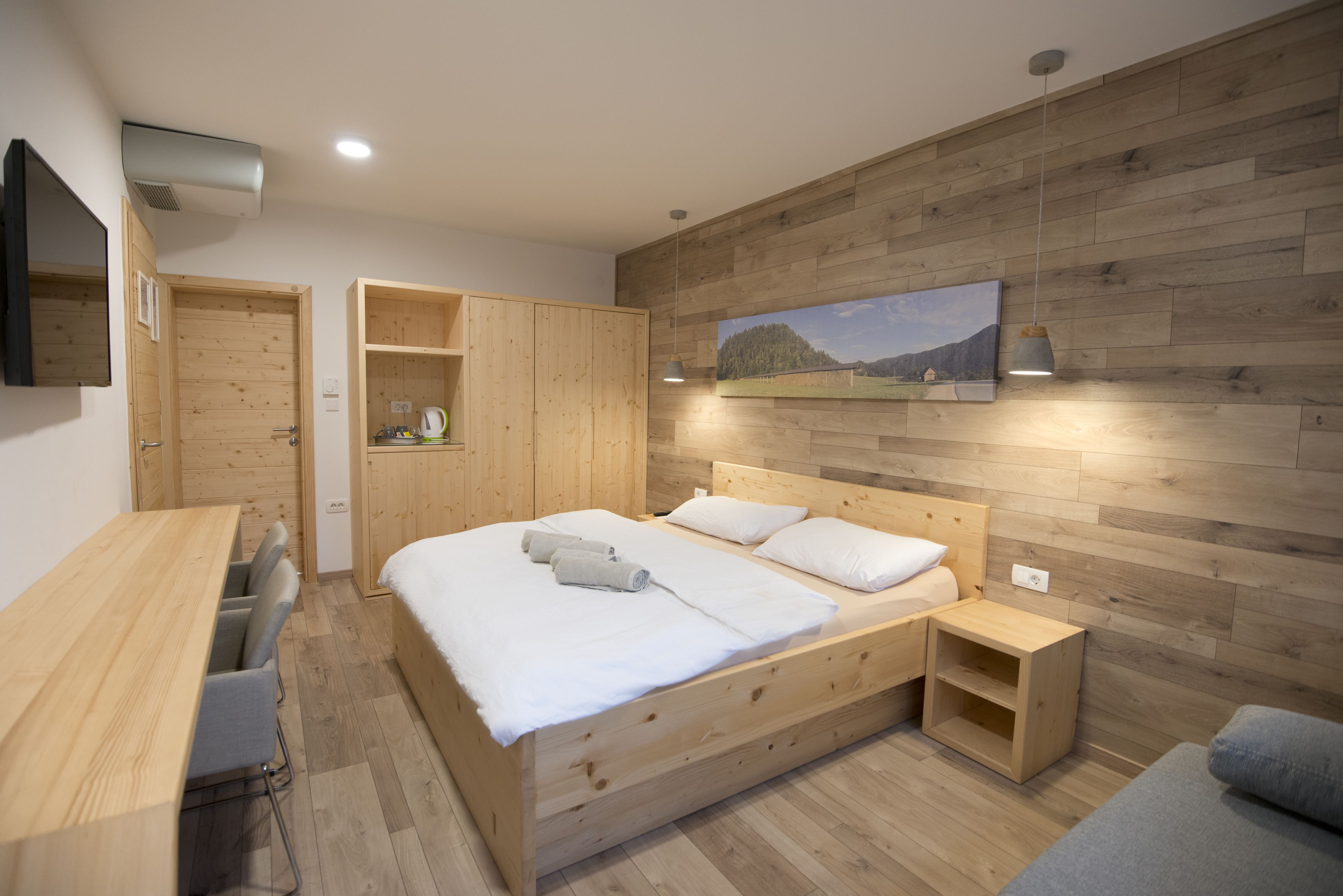 A bedroom with a wooden bed, a desk, and a wardrobe.
