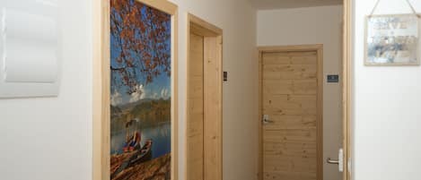 A hallway with wooden doors, a framed painting of a lake scene, and a sign that says "GIVE WATCH LITE".