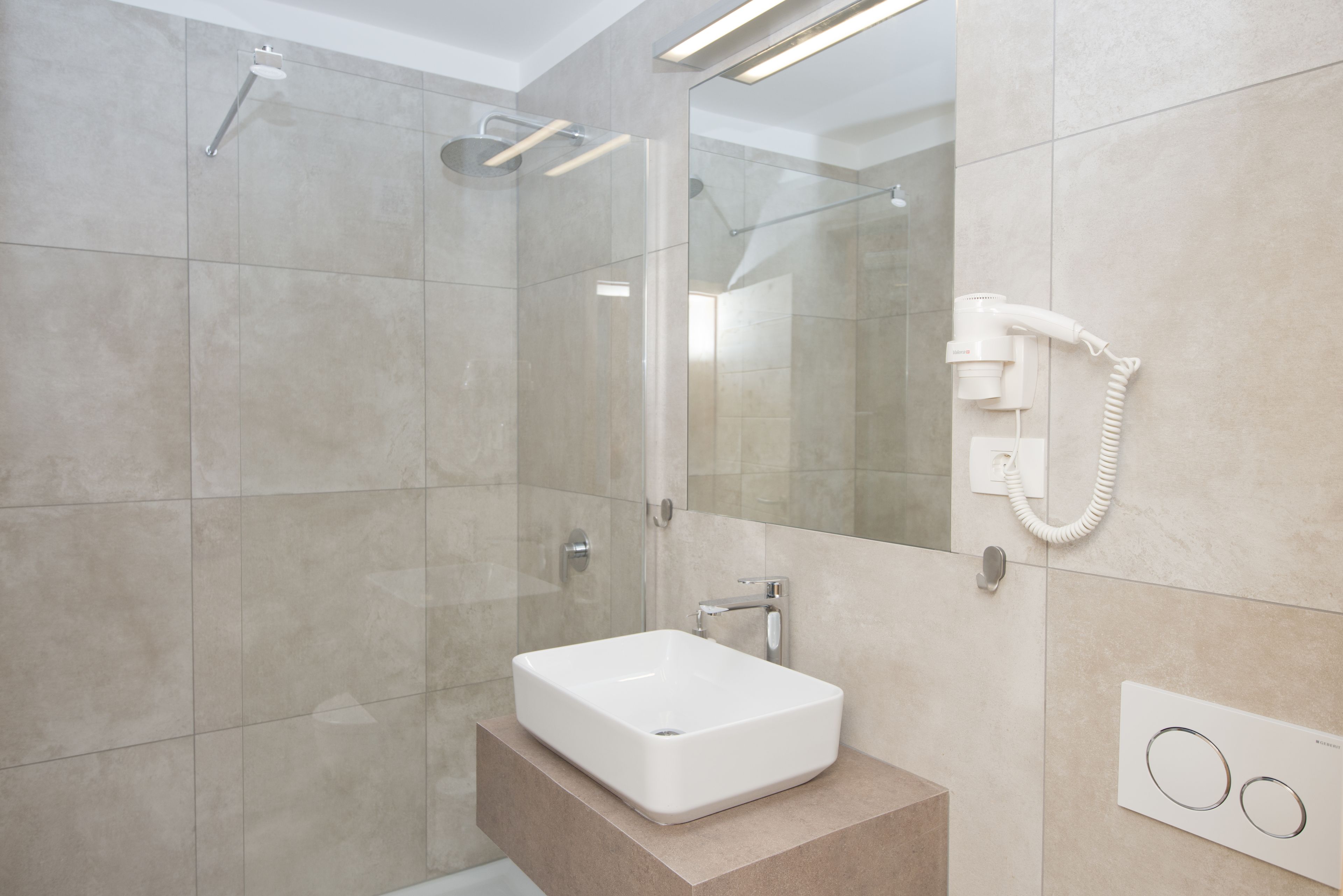 A modern bathroom with a glass-enclosed shower, a white sink, and a built-in telephone.