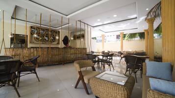 A spacious indoor area with wicker furniture, a bar area with mirrors, and a ceiling with hanging lights.