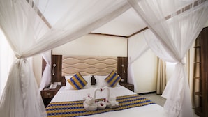 Une chambre d’hôtel avec un lit, une table de chevet, un téléphone et un lit à baldaquin.