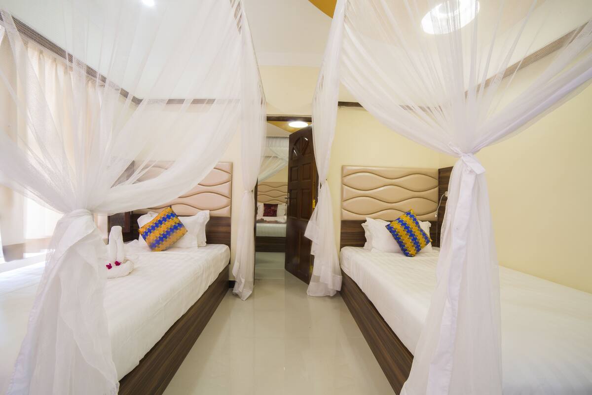 Ein Hotelzimmer mit zwei Betten, jeweils mit Baldachin und Kopfteil.