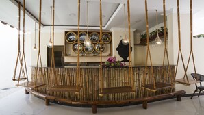 Un hall d’entrée doté d’un banc central en bois, de luminaires suspendus et d’un mur orné de miroirs encadrés et d’une décoration en silhouette.