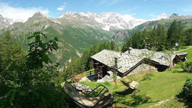 A mountain lodge with stone roofs, surrounded by lush greenery and snow-capped peaks. - Baita Ancienne Bergerie (Valtournenche)