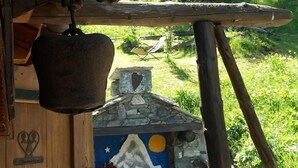 A rustic cabin with a wooden exterior, a stone chimney, and a hanging bell. - Baita Ancienne Bergerie (Valtournenche)