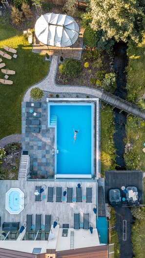 An aerial view of a rooftop pool area with a diving board, lounge chairs, and a small hot tub. - Hotel Lamm (Heimbuchenthal)