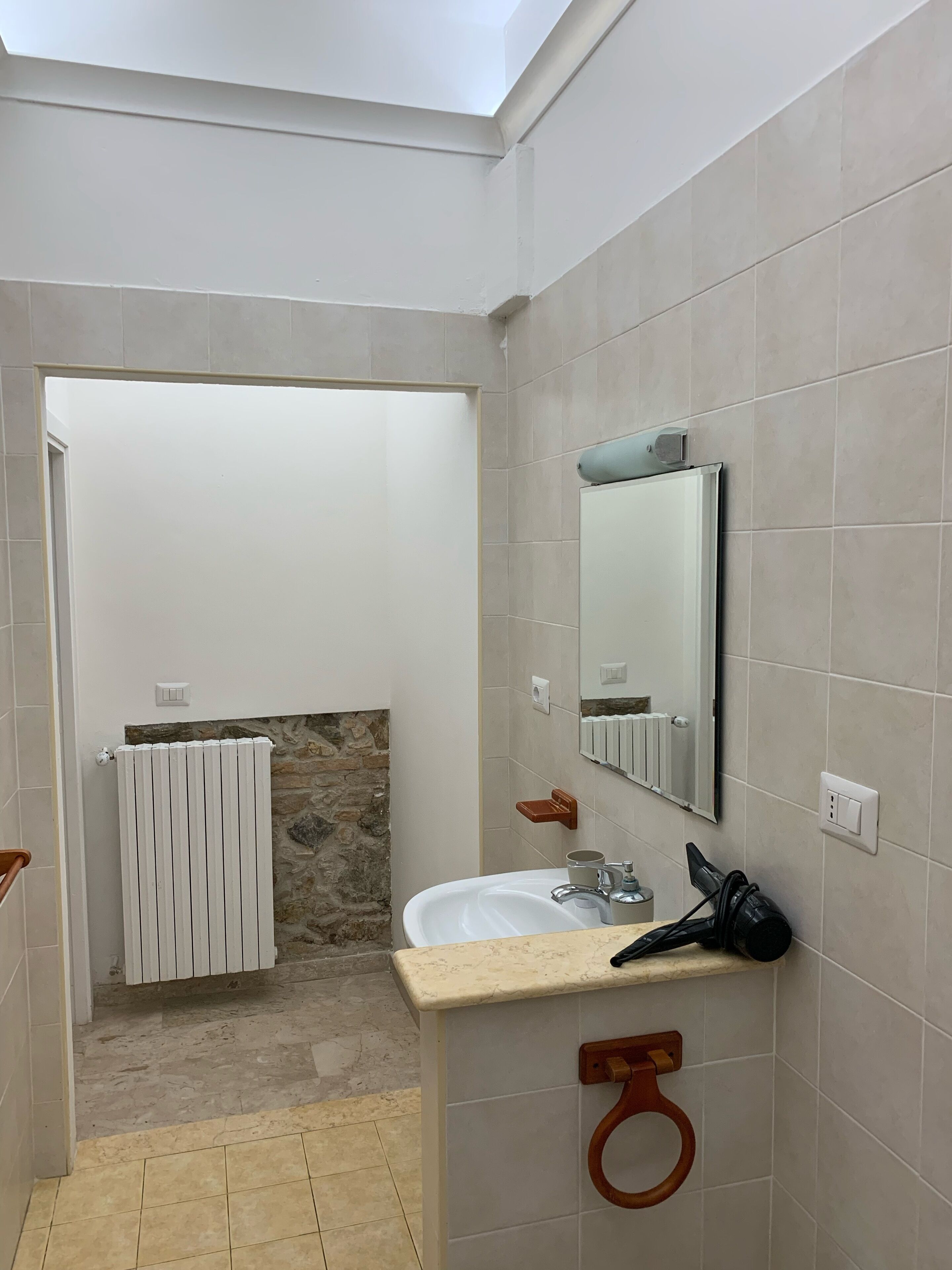 A bathroom with a white sink, a mirror, a towel rack, and a shower area.