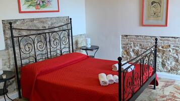 A room with a bed, a small table, and two framed artworks on the walls.