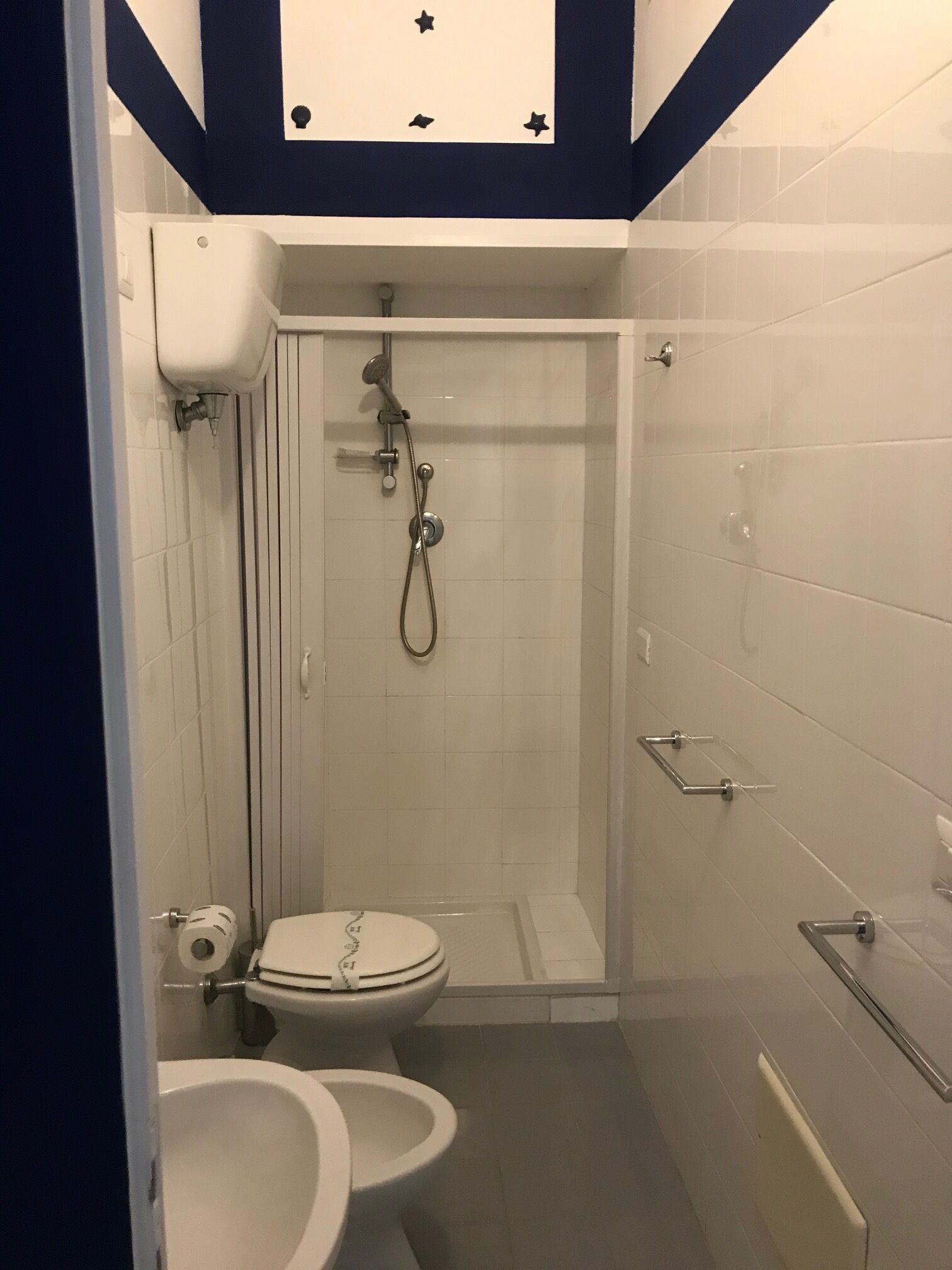 A small bathroom with a toilet, sink, and shower.