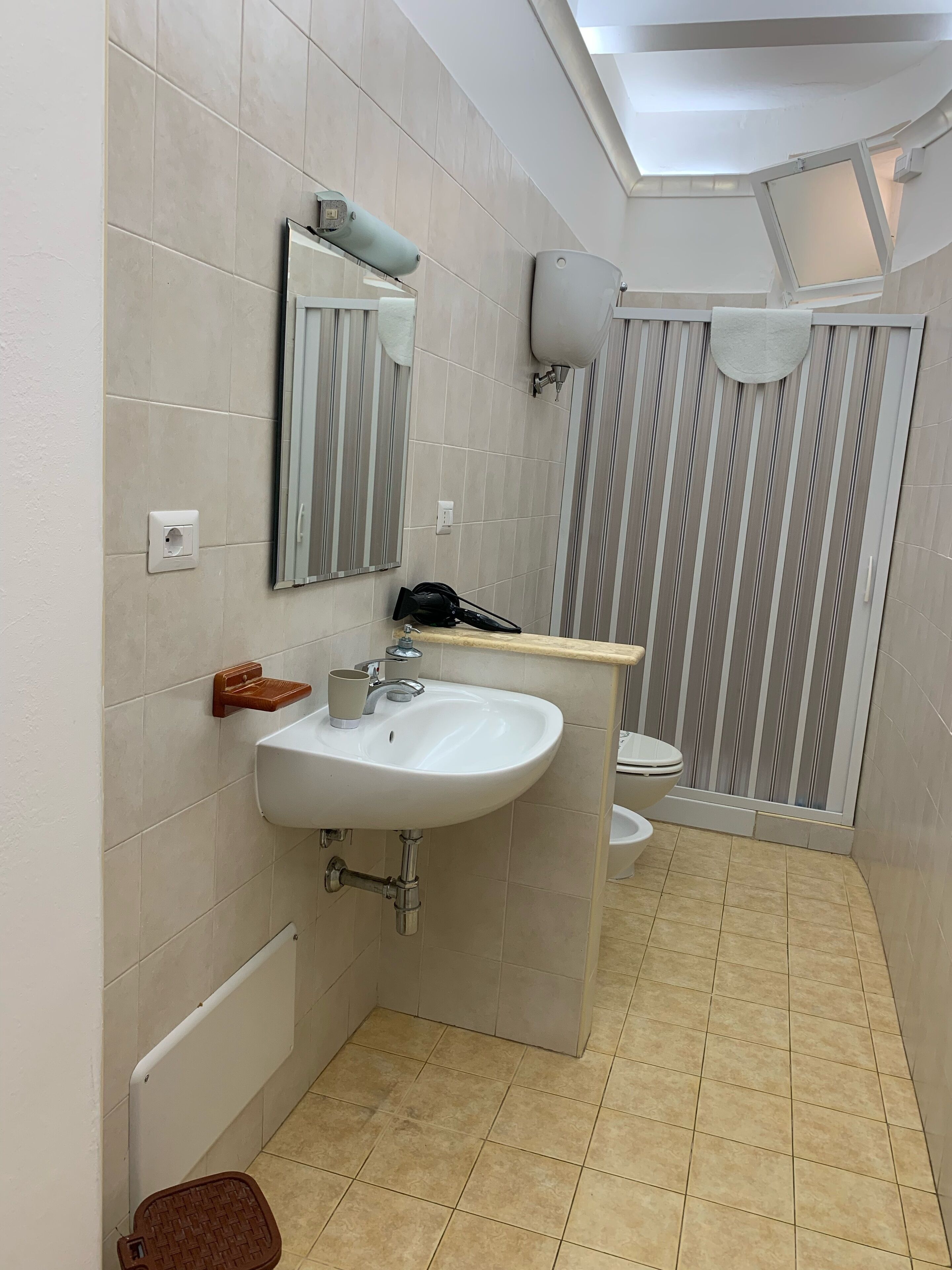 Une salle de bain moderne avec un lavabo blanc, un miroir et un rideau de douche à rayures.