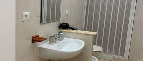 Un baño moderno con lavamanos blanco, espejo y cortina de ducha a rayas.