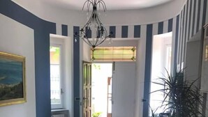Un couloir avec un canapé beige, une plante en pot et un lustre.