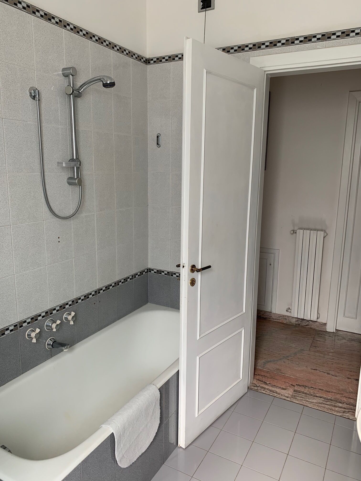 A bathroom with a bathtub, a shower, and a door leading to another room.