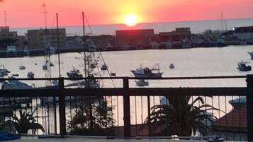 Una marina con barcos y un atardecer al fondo.