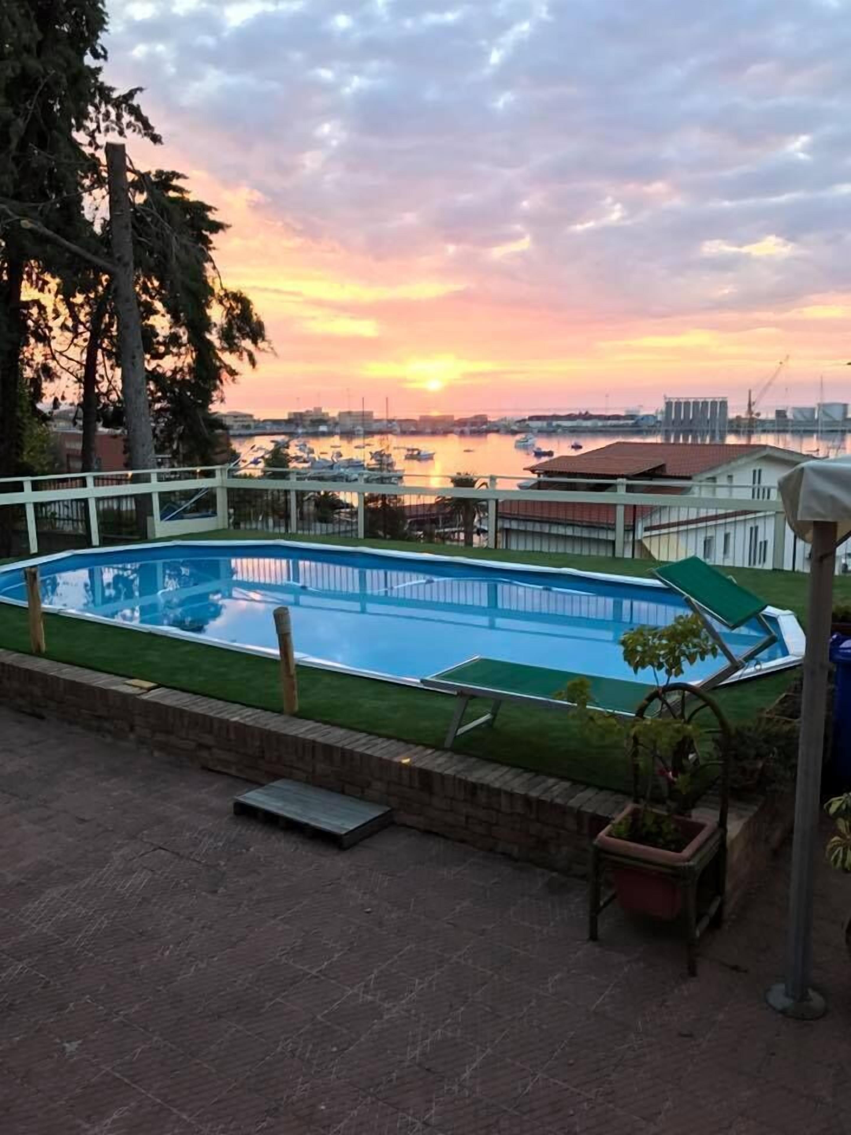 Una piscina con vistas a un puerto deportivo y al atardecer.
