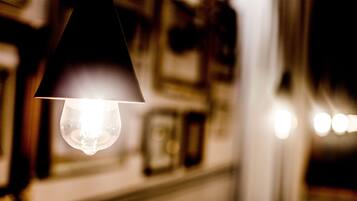 A close-up of a hanging light bulb in a dimly lit room with blurred background details.