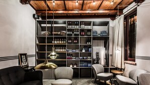 Una sala moderna con techo de madera, una estantería llena de botellas y un sofá negro.
