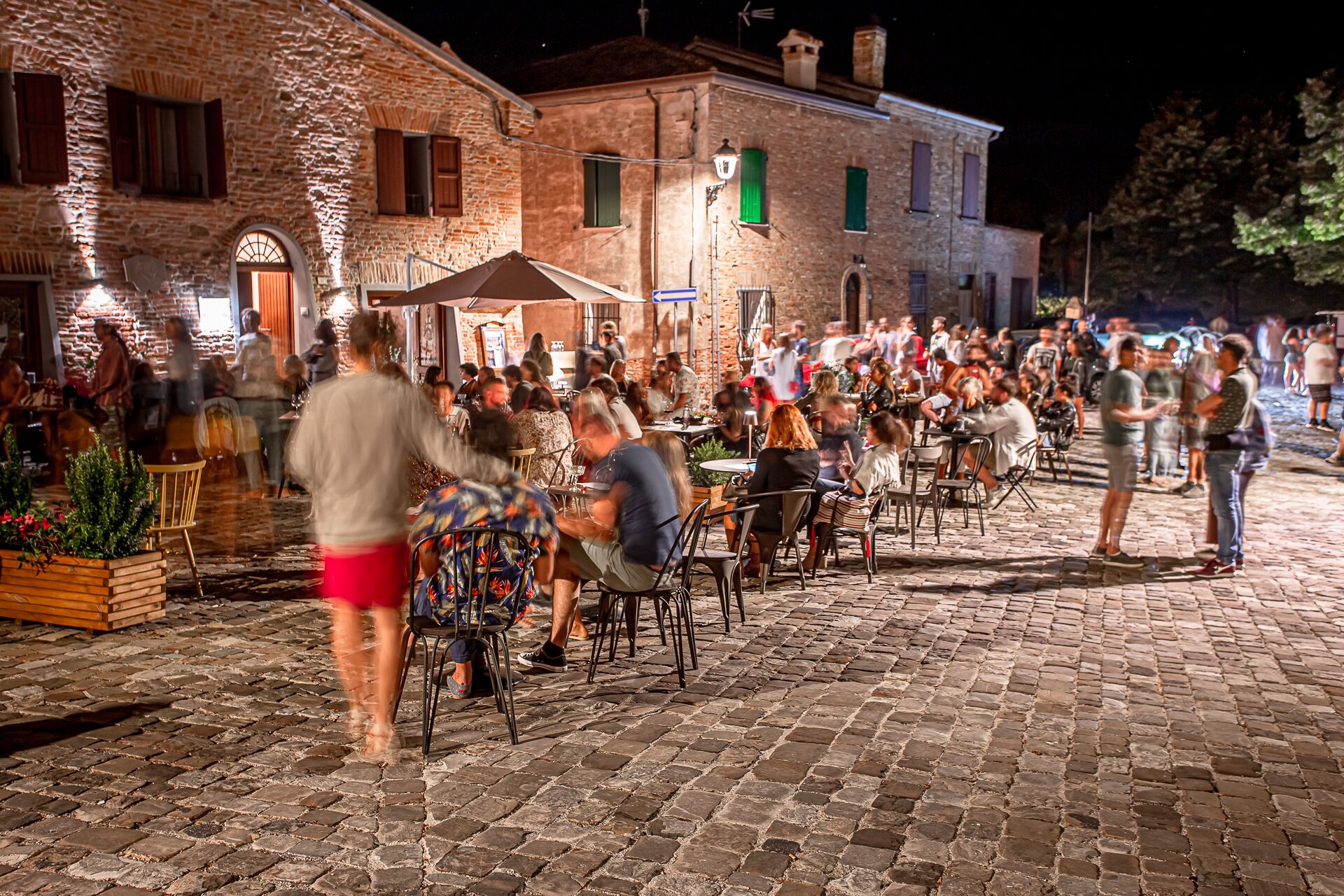 An outdoor dining area with stone paving and brick buildings in the background.