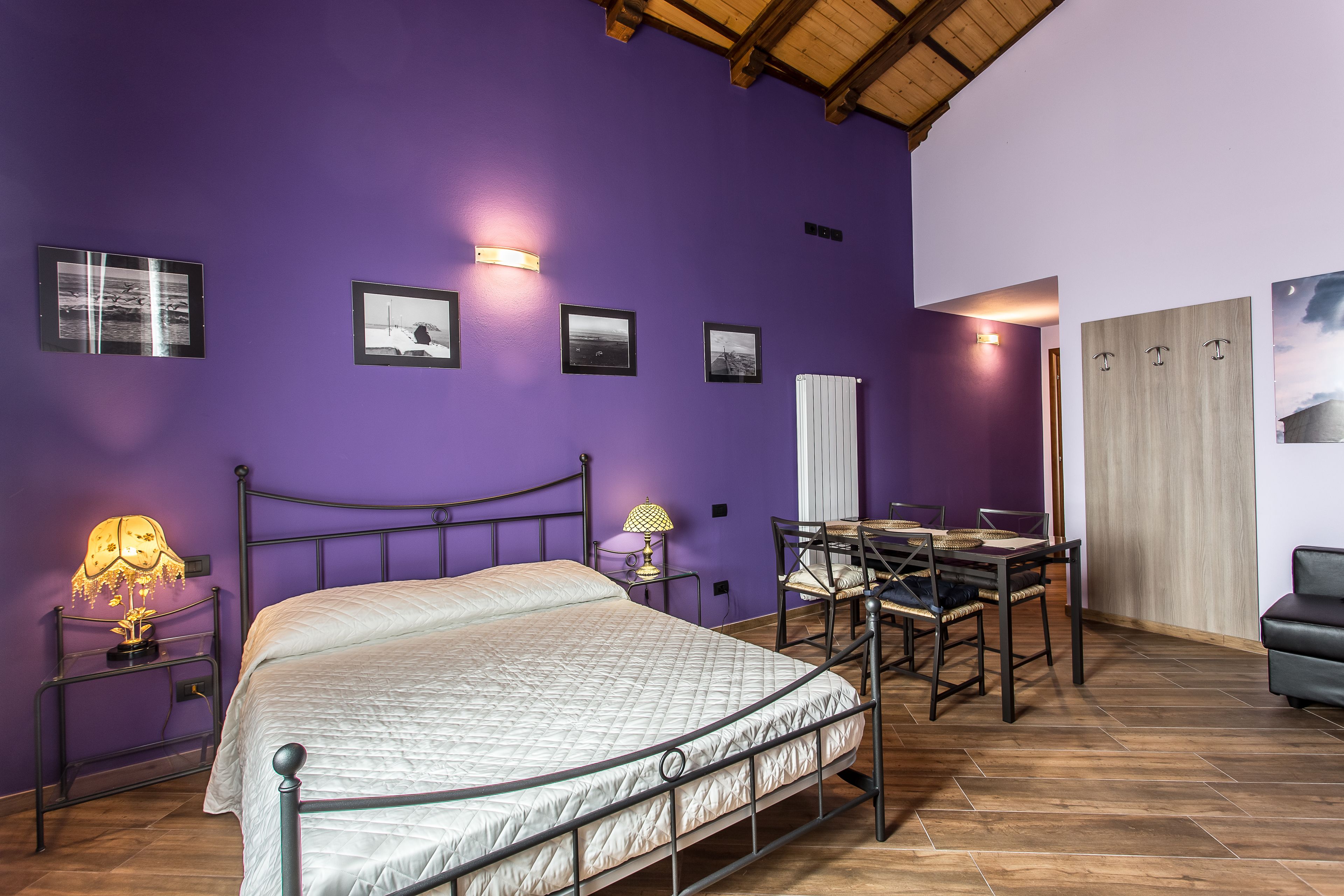 A bedroom with a bed, bedside tables, a desk with chairs, and a wardrobe.