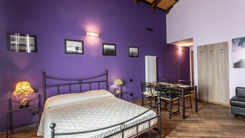 A bedroom with a bed, bedside tables, a desk with chairs, and a wardrobe.