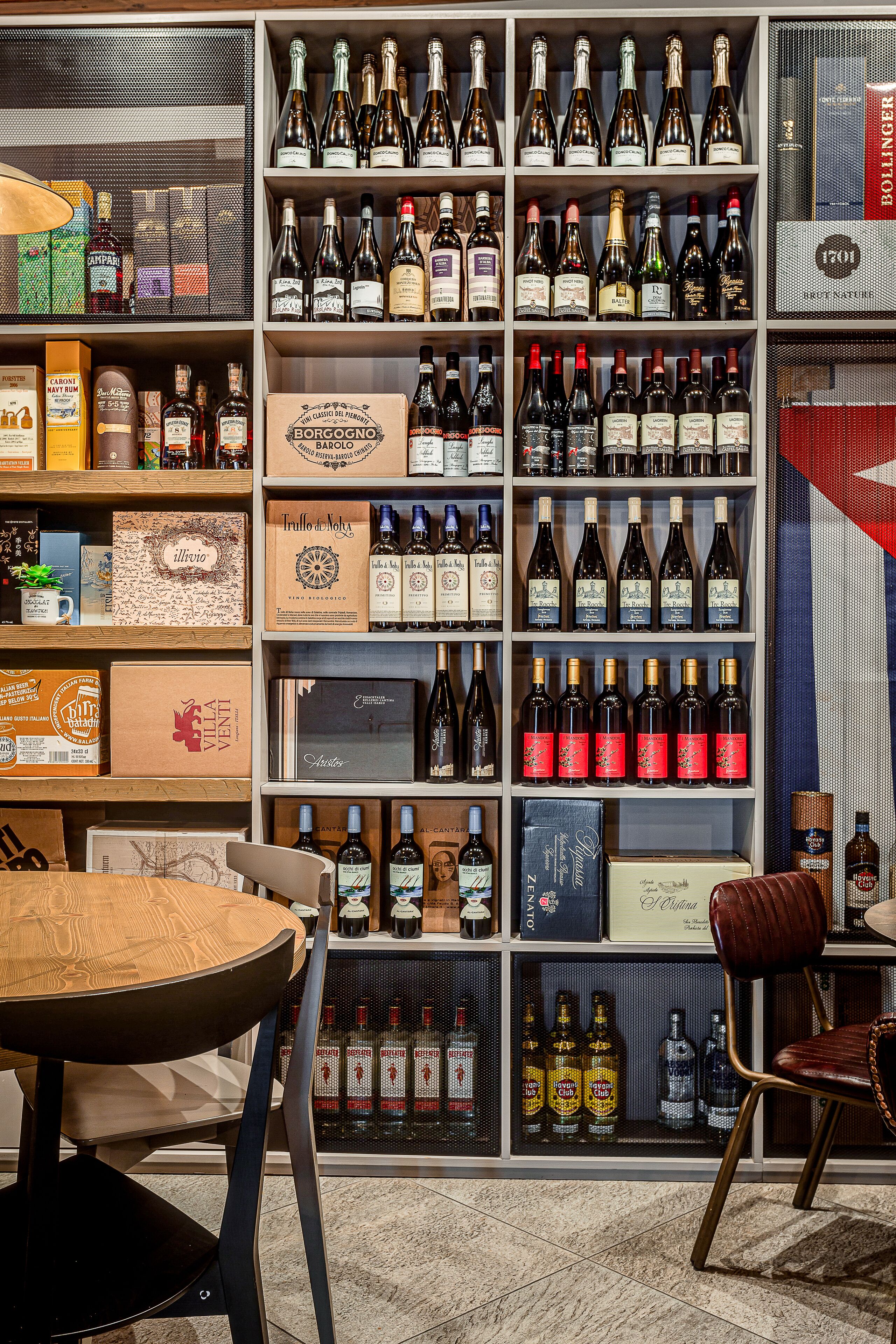 Una tienda de vinos y licores con estantes llenos de botellas y cajas de diversos tipos.