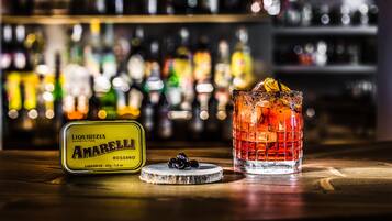 Eine Bar mit einer Flasche Amarella Likör, einem Glas mit Eiswürfeln und einem Untersetzer mit ein paar Oliven.