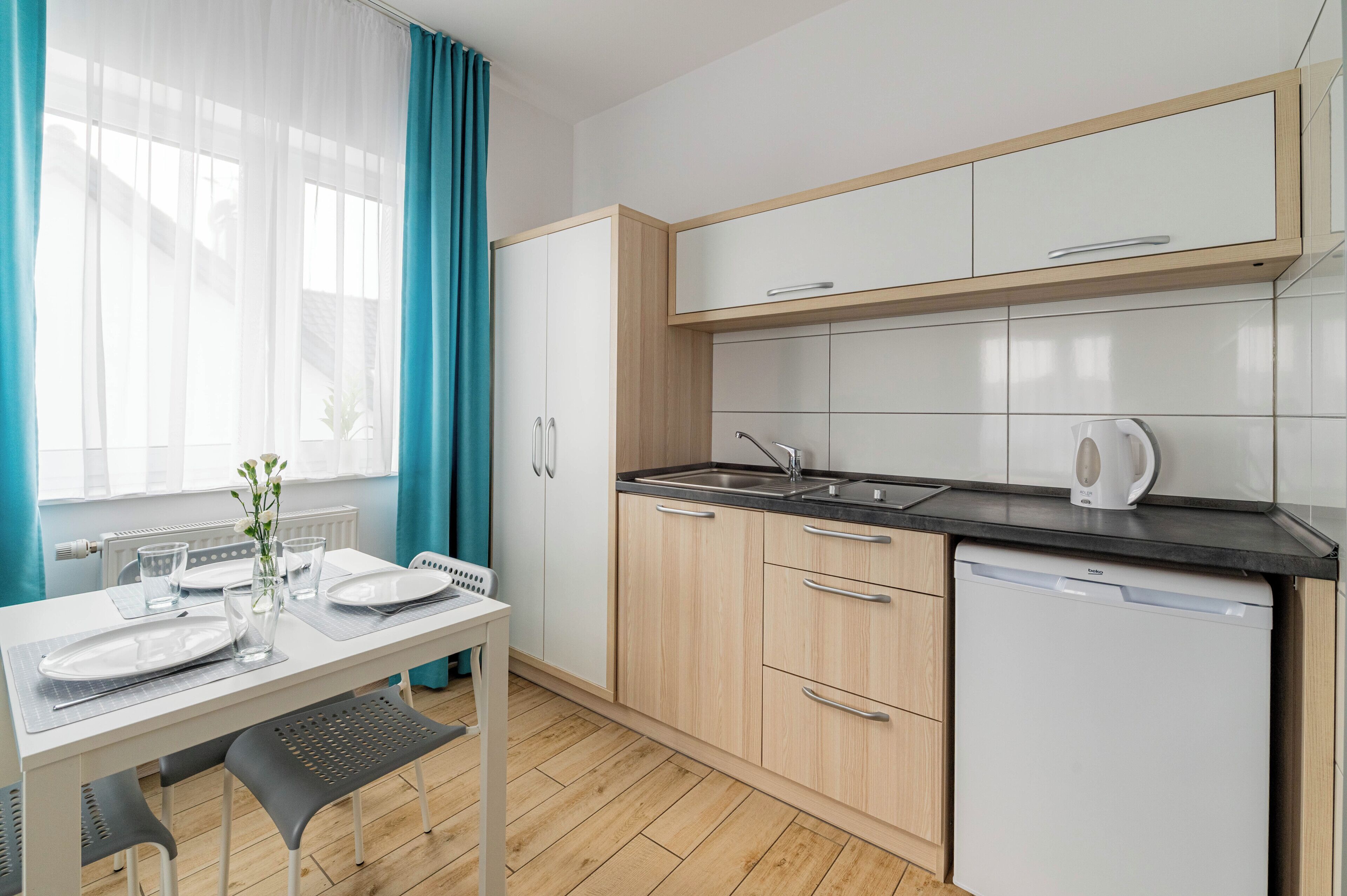 Een moderne keuken met een vaatwasser, een spoelbak en een raam met gordijnen.