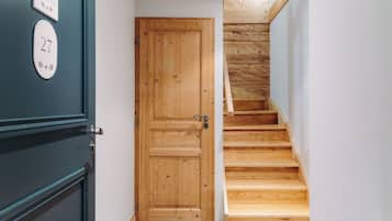 A wooden door with a number plate, a staircase with wooden steps, and a wall with a nameplate.