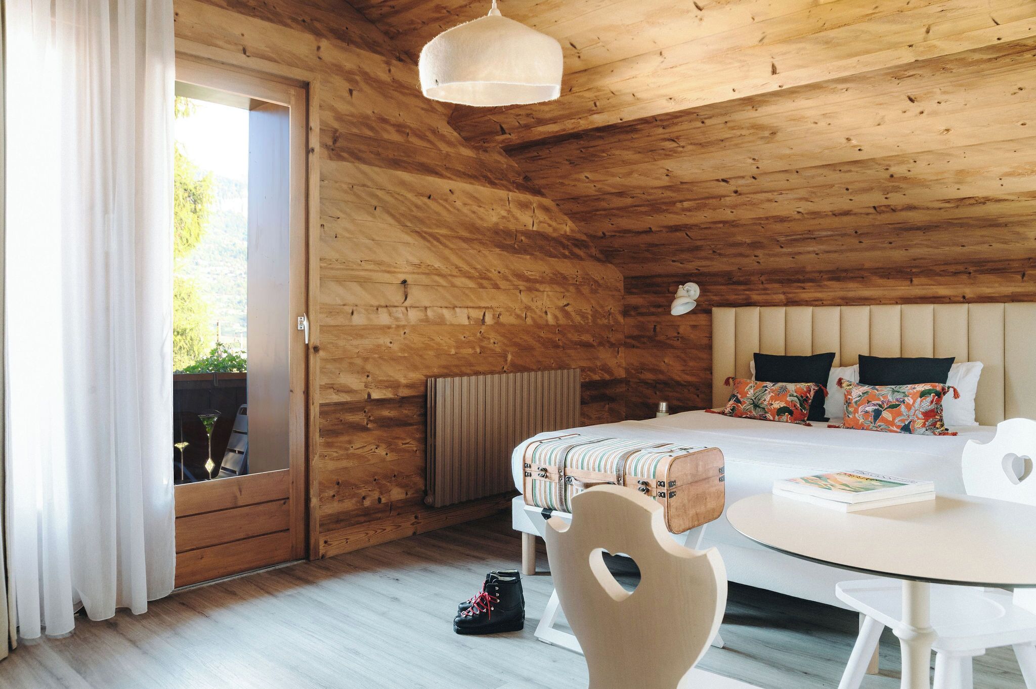 A wooden cabin bedroom with a bed, a round table, and a chair.