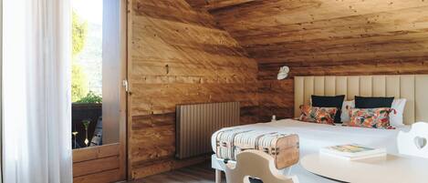 A wooden cabin bedroom with a bed, a round table, and a chair.