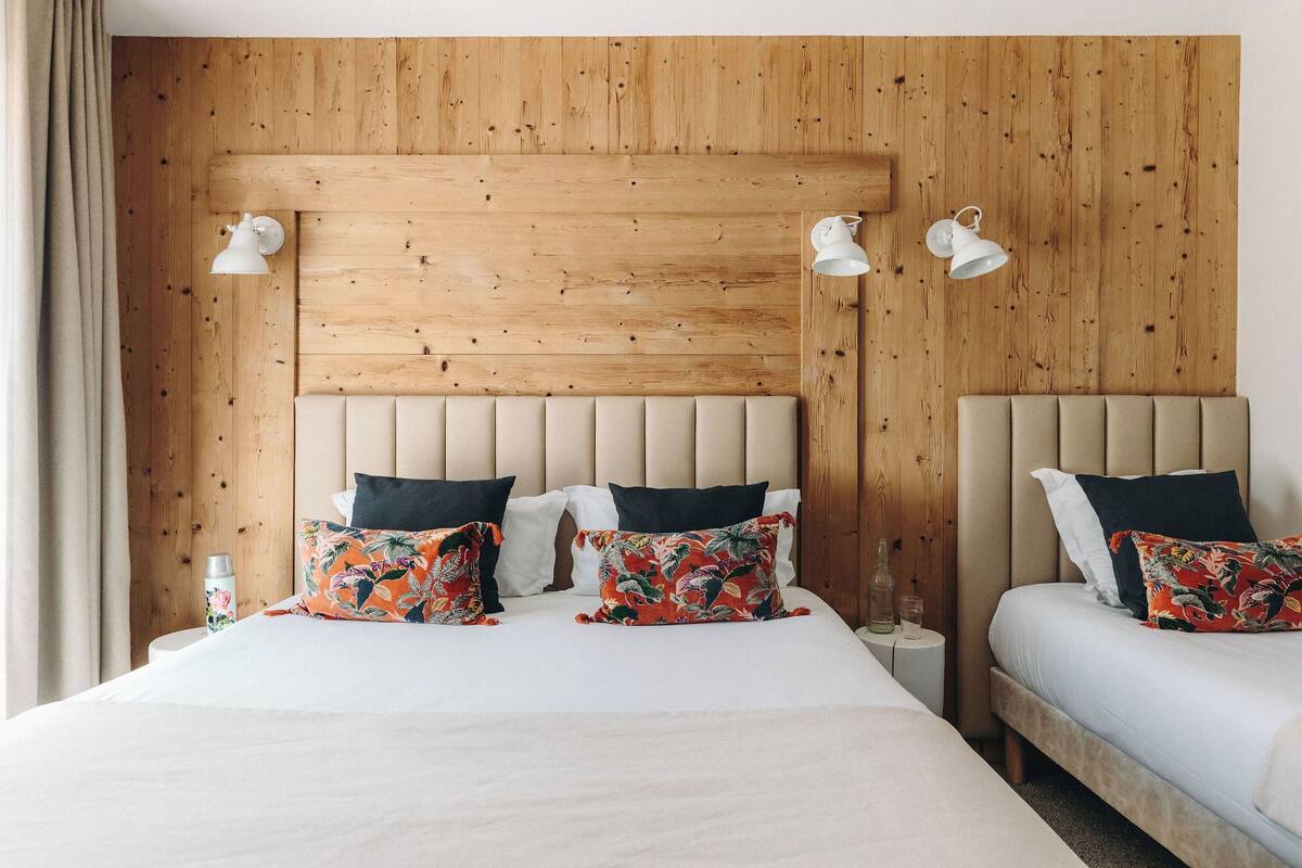 Un lit double avec une tête de lit en bois, deux tables de chevet et des coussins à motifs floraux.