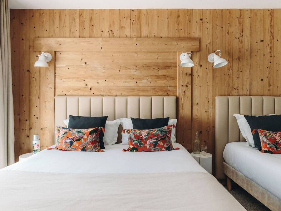 Una cama doble con cabecera de madera, dos mesitas de noche y almohadas estampadas con motivos florales.