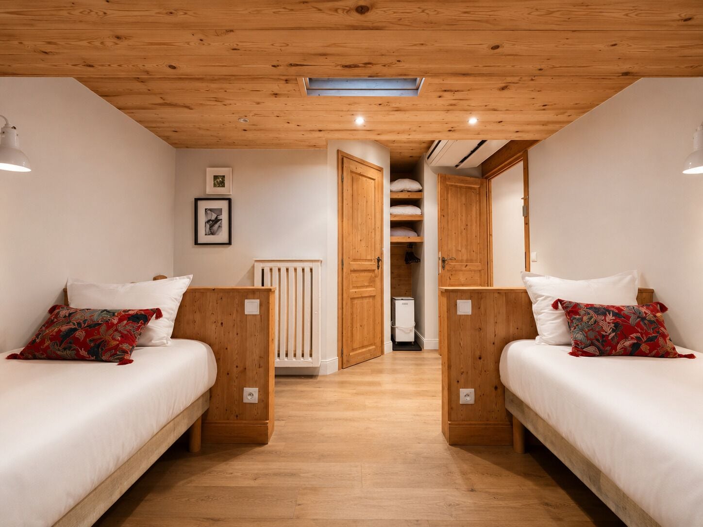 Une chambre avec deux lits, des têtes de lit en bois, du linge de lit blanc, un radiateur et un petit appareil de chauffage blanc.