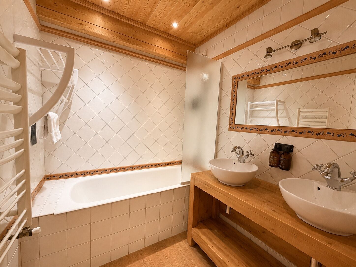 Un baño con bañera, dos lavamanos, un espejo y un perchero para toallas.