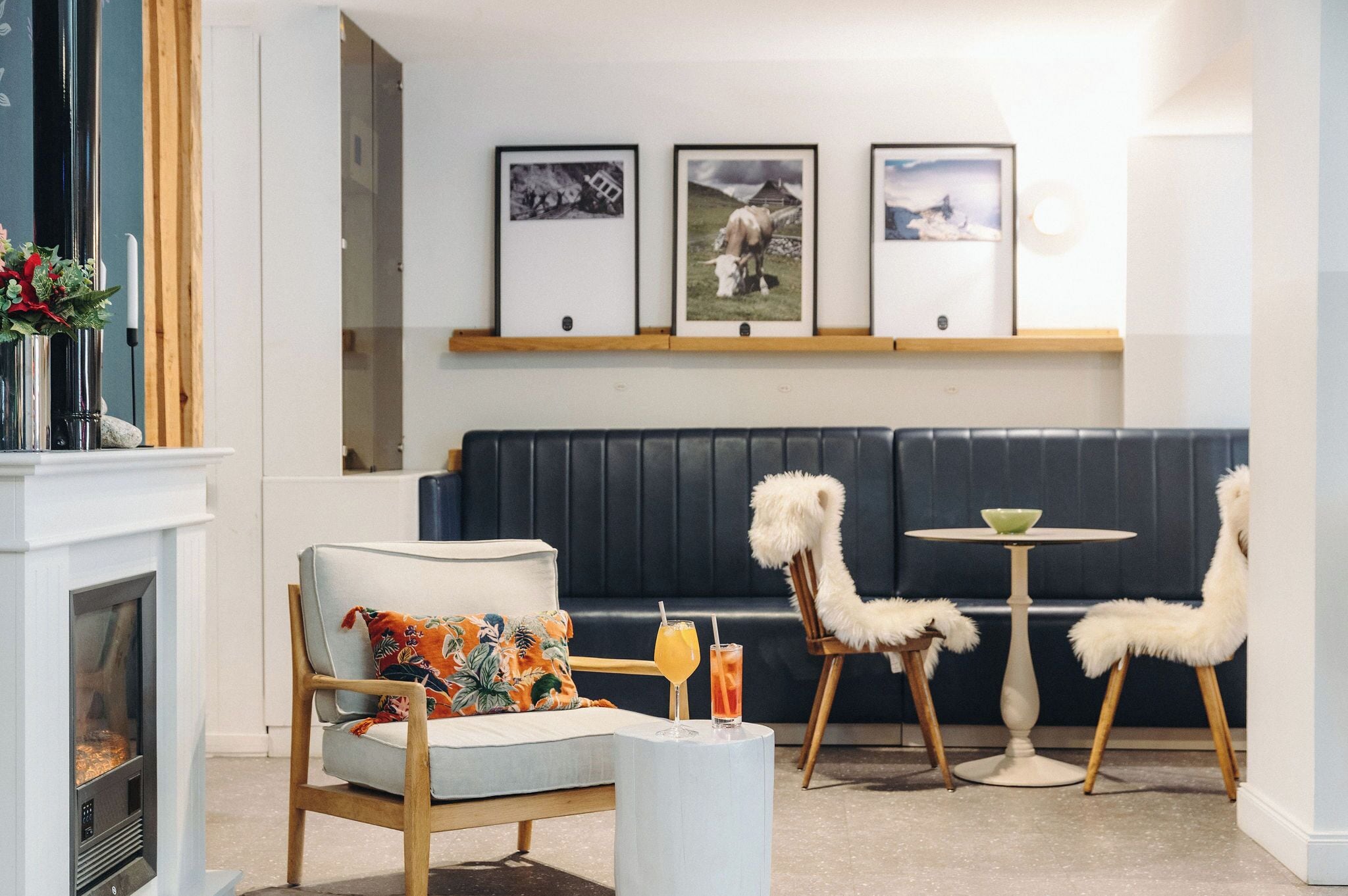 Un salon moderne avec une cheminée, un canapé, deux fauteuils et une petite table sur laquelle sont posées des boissons.