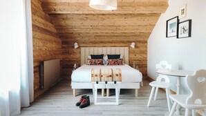 Un dormitorio con paneles de madera, una cama, mesitas de noche y una pequeña mesa con sillas.
