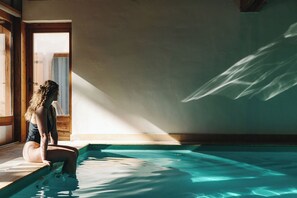 A person sitting by a pool with sunlight casting shadows on the wall. - Hôtel des 2 Gares (Saint-Gervais-les-Bains)