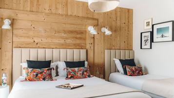 A bedroom with a wooden headboard, two bedside tables, a bed with floral pillows, and a hanging light fixture.