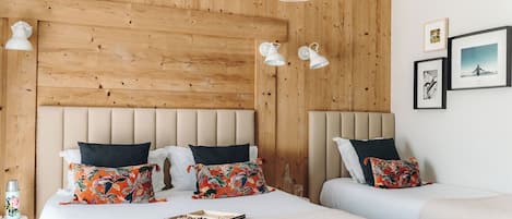Un dormitorio con cabecera de madera, dos mesitas de noche, cama con almohadas estampadas y una lámpara colgante.