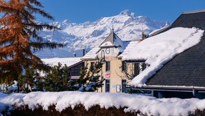 Un edificio con una torre de reloj, un letrero de restaurante y montañas al fondo.
