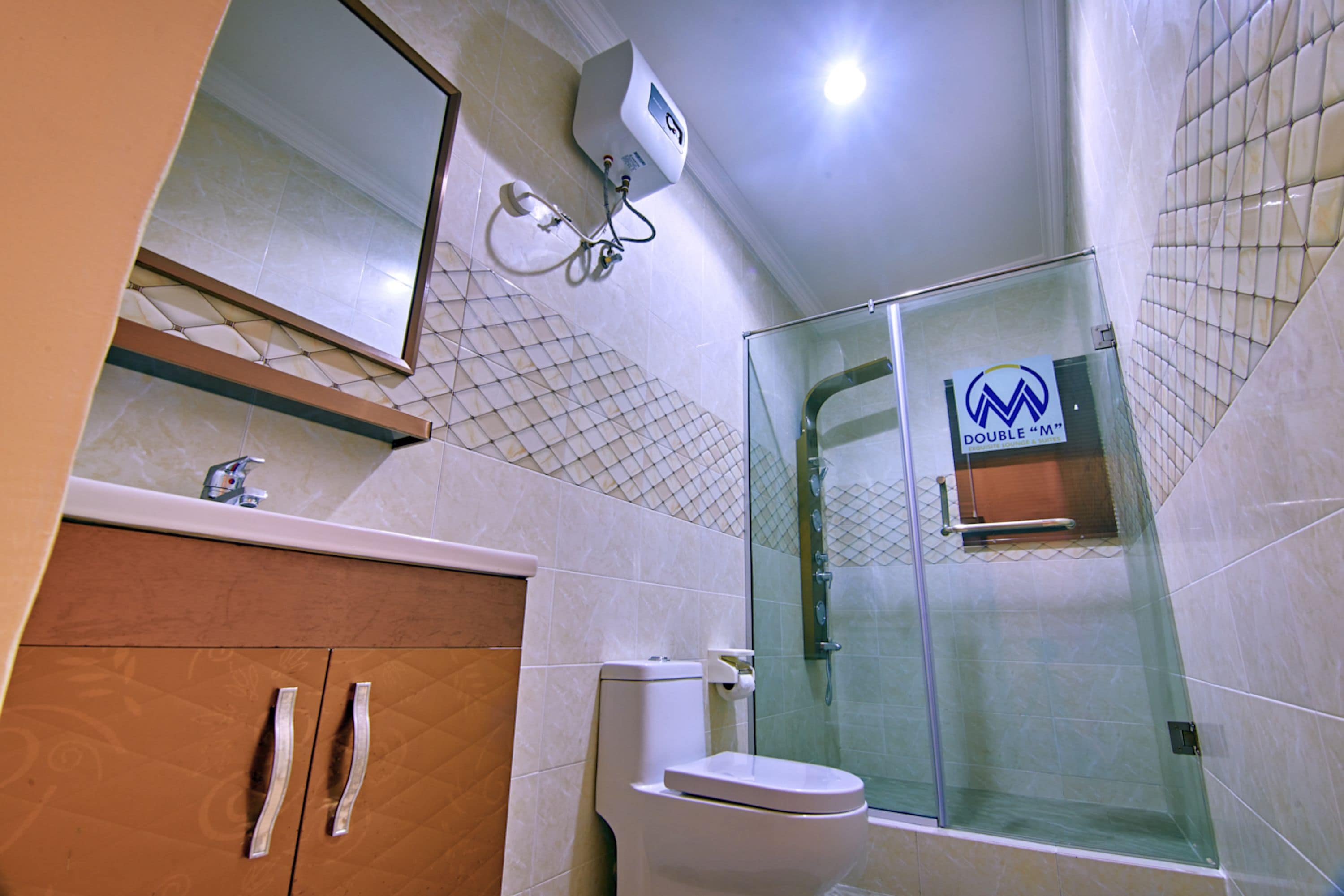Un baño con ducha de vidrio, inodoro y lavamanos con espejo.