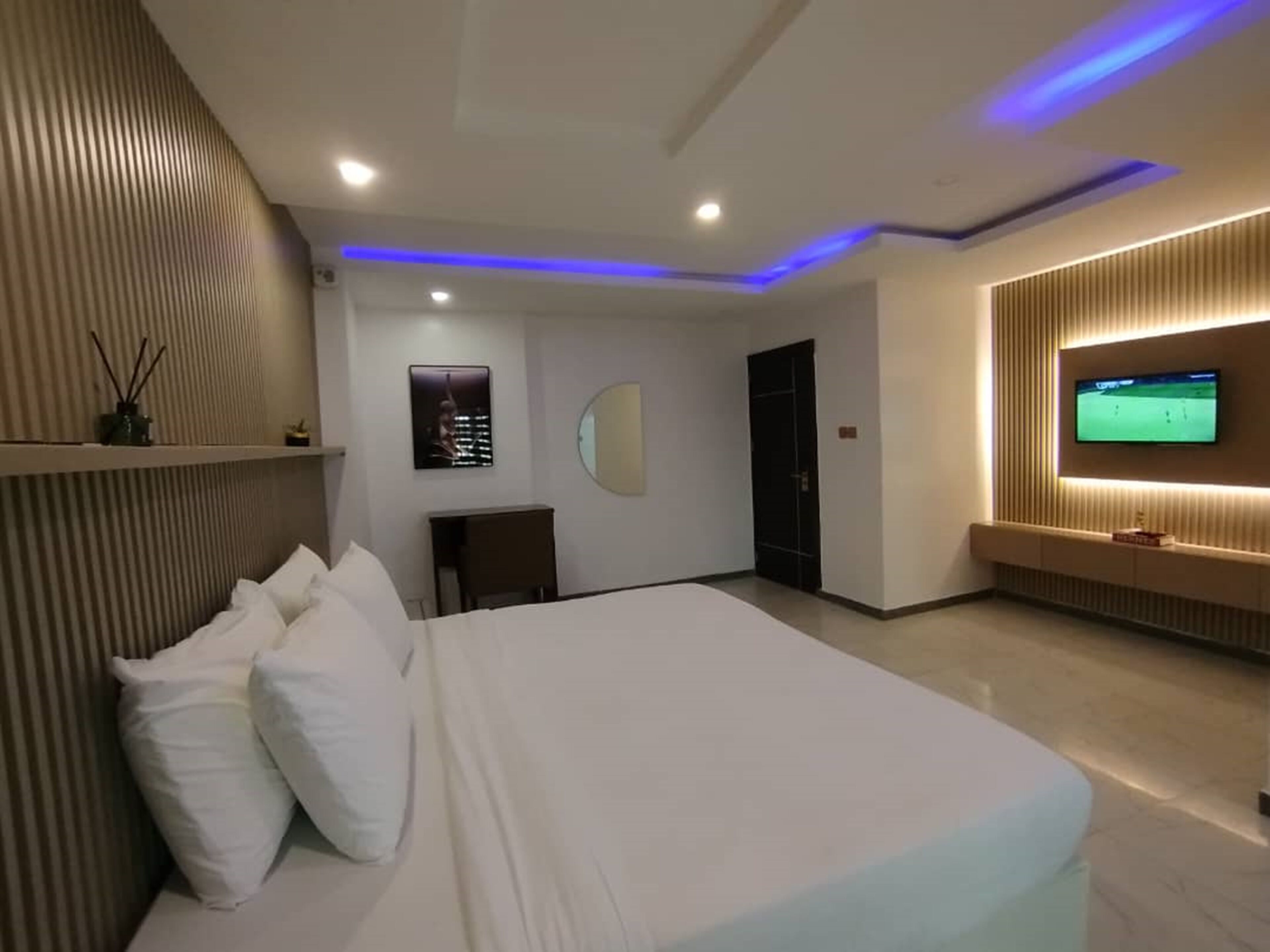 A modern hotel room with a large bed, a TV mounted on the wall, and a desk with a chair.