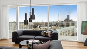 Una sala de estar moderna con un ventanal grande, un sofá negro, una mesa de centro y un televisor.