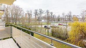 Un balcon donnant sur un parking, des arbres et des bâtiments situés au loin.